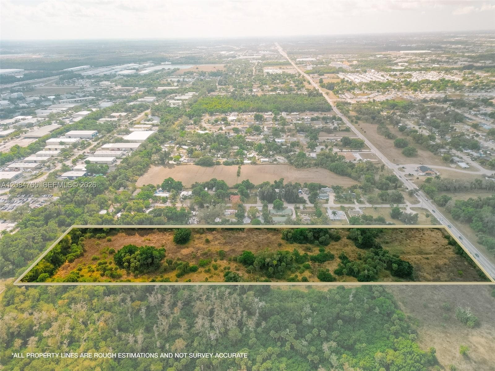Wide-angle aerial shot displaying the property's rural charm, framed by open fields and scattered vegetation typical of South Florida land.