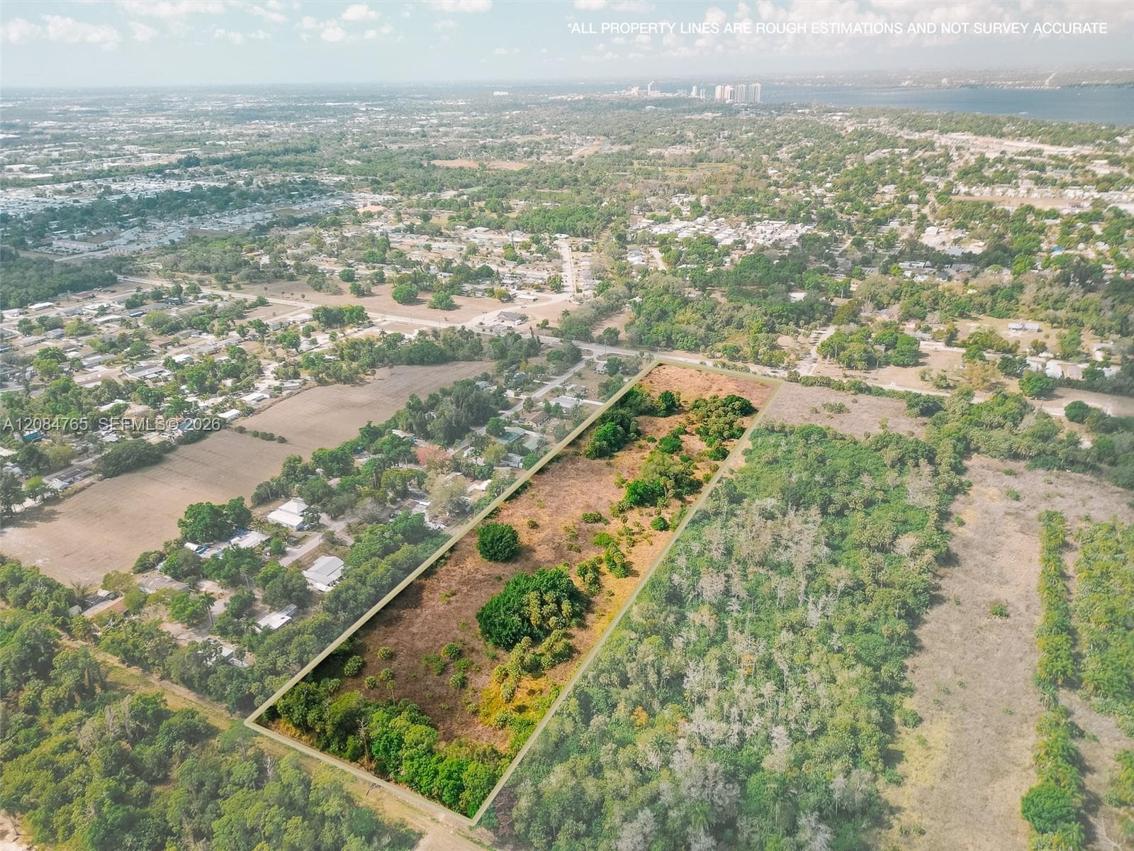 Expansive aerial view capturing the natural landscape and tree-lined perimeter of this buildable lot, ideally positioned near local rooftops and infrastructure.